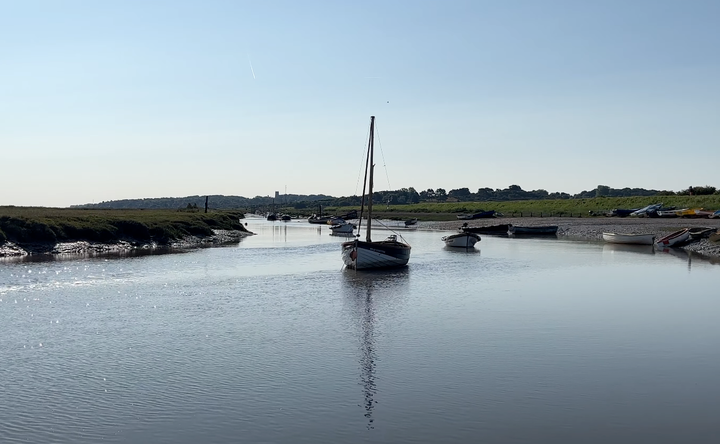 photo of Morston, with a moored sailboat in the middle of the estuary